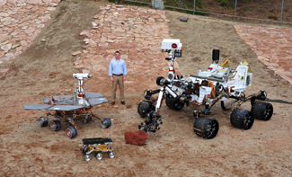 Keith Comeaux standing in an open field surrounded by rovers