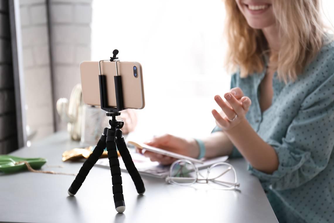 woman using her phone on a tripod to record a video