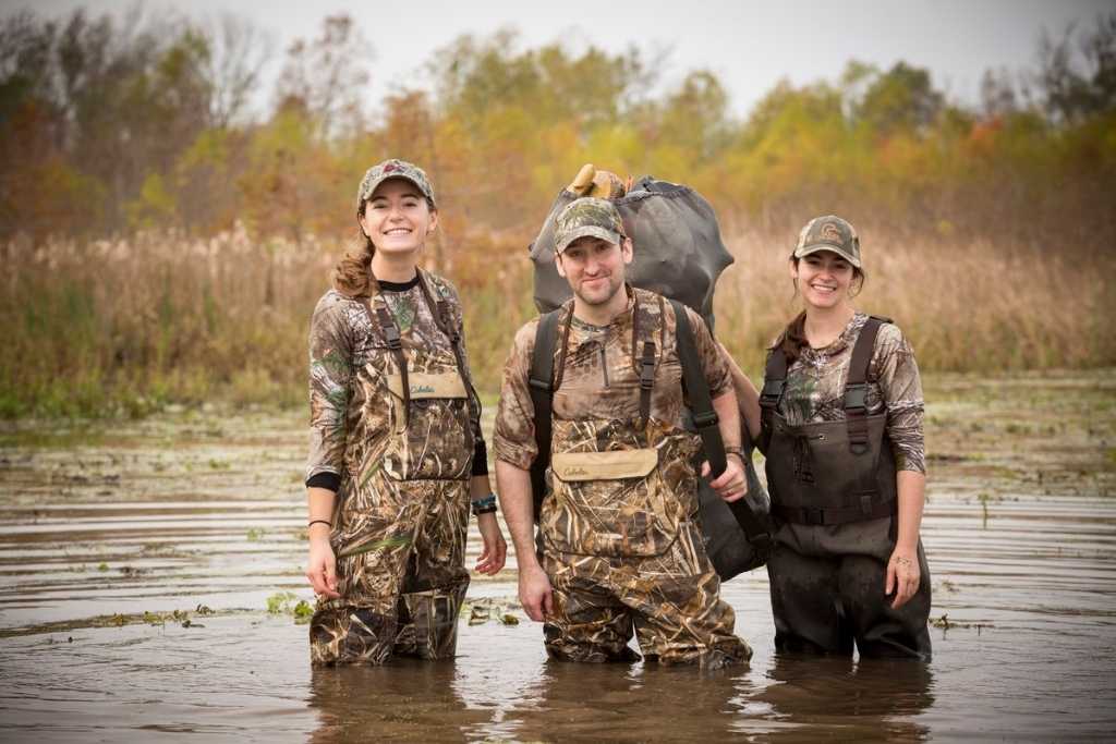 three people in camoflauge stand in water