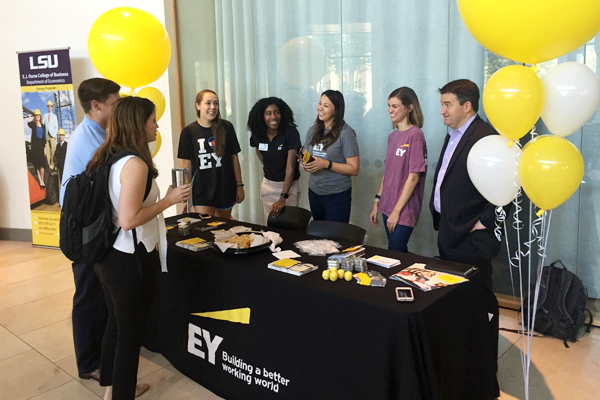 two students talk with representatives behind an EY table