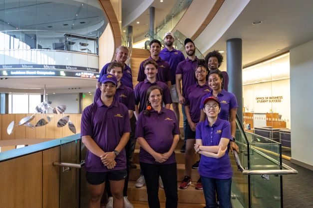 Group of people standing on stair in purple polos