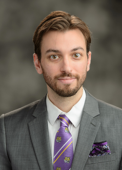 Man in suit in front of a grey backdrop - Aaron Gleibermann headshot 