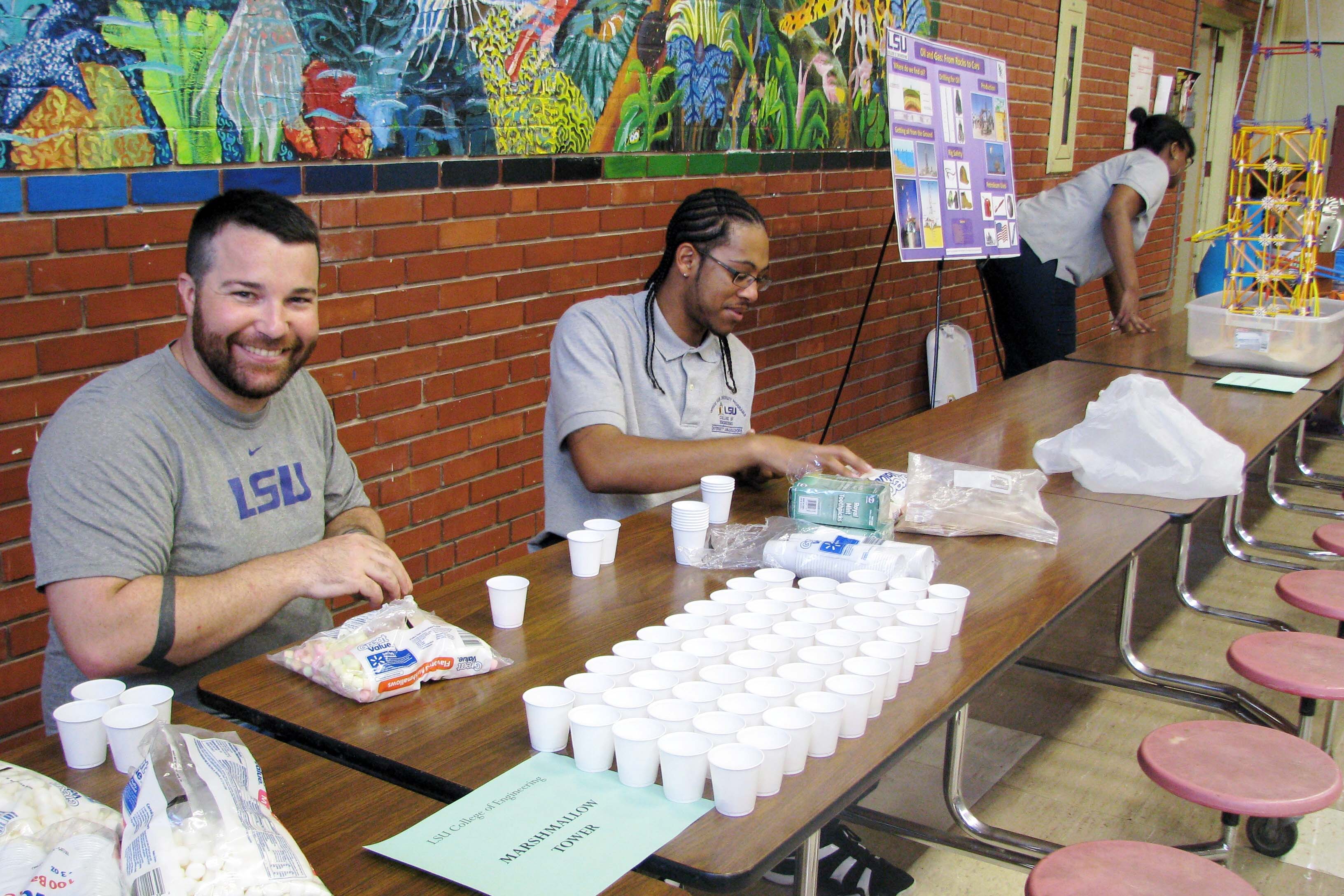 Two people sitting at cafeteria table with cups