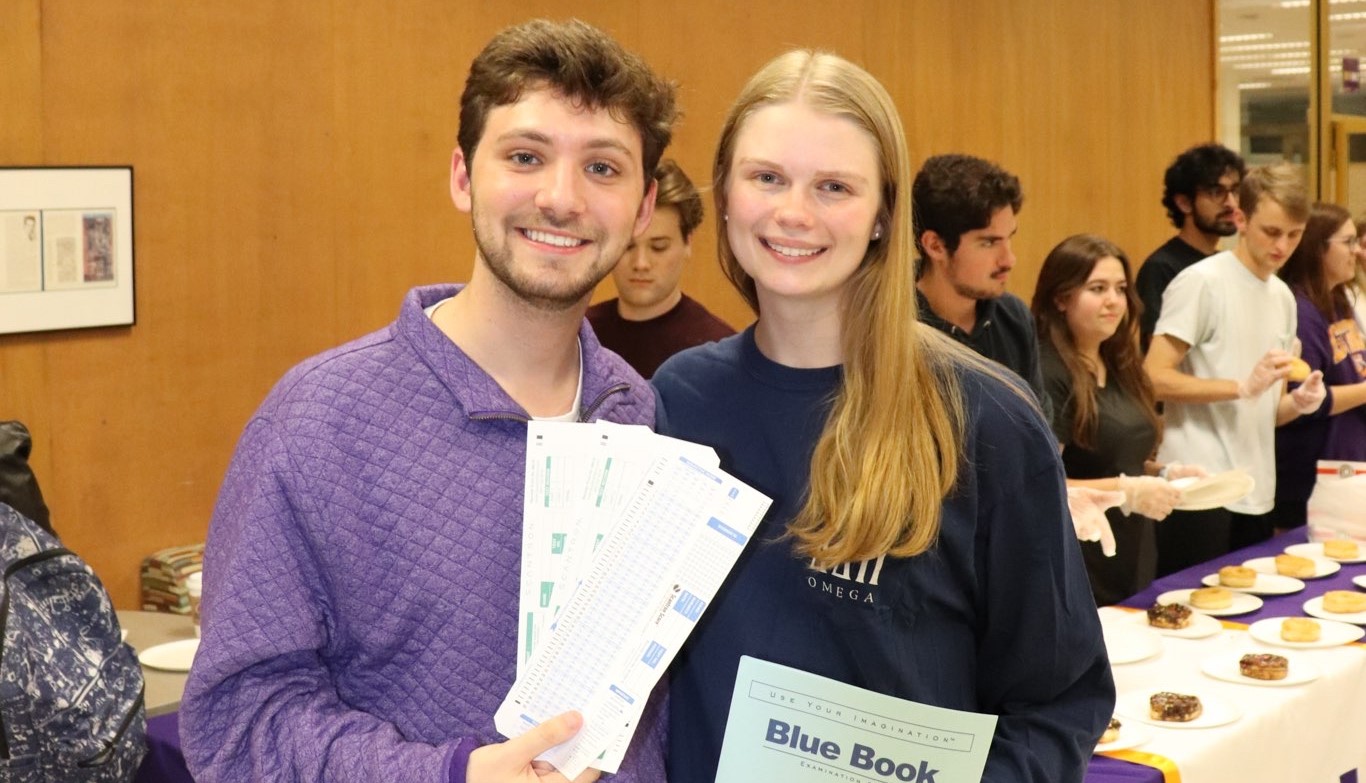 matthew and emma smiling holding bluebooks and scantrons 